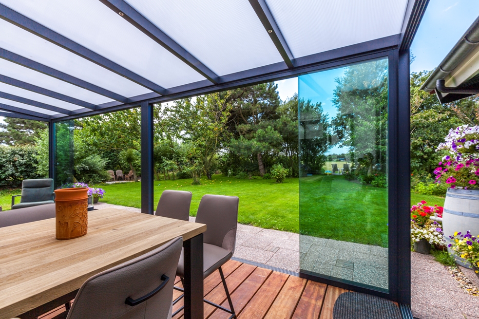 Glass veranda structure with aluminum frame and garden view